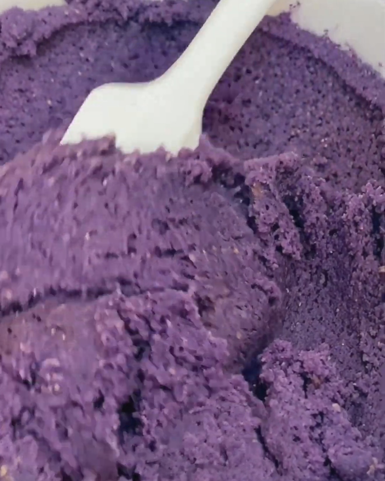 Impasto di biscotti ube viola intenso piegato con una spatola bianca dopo aver aggiunto Ube Nolia polvere di ube