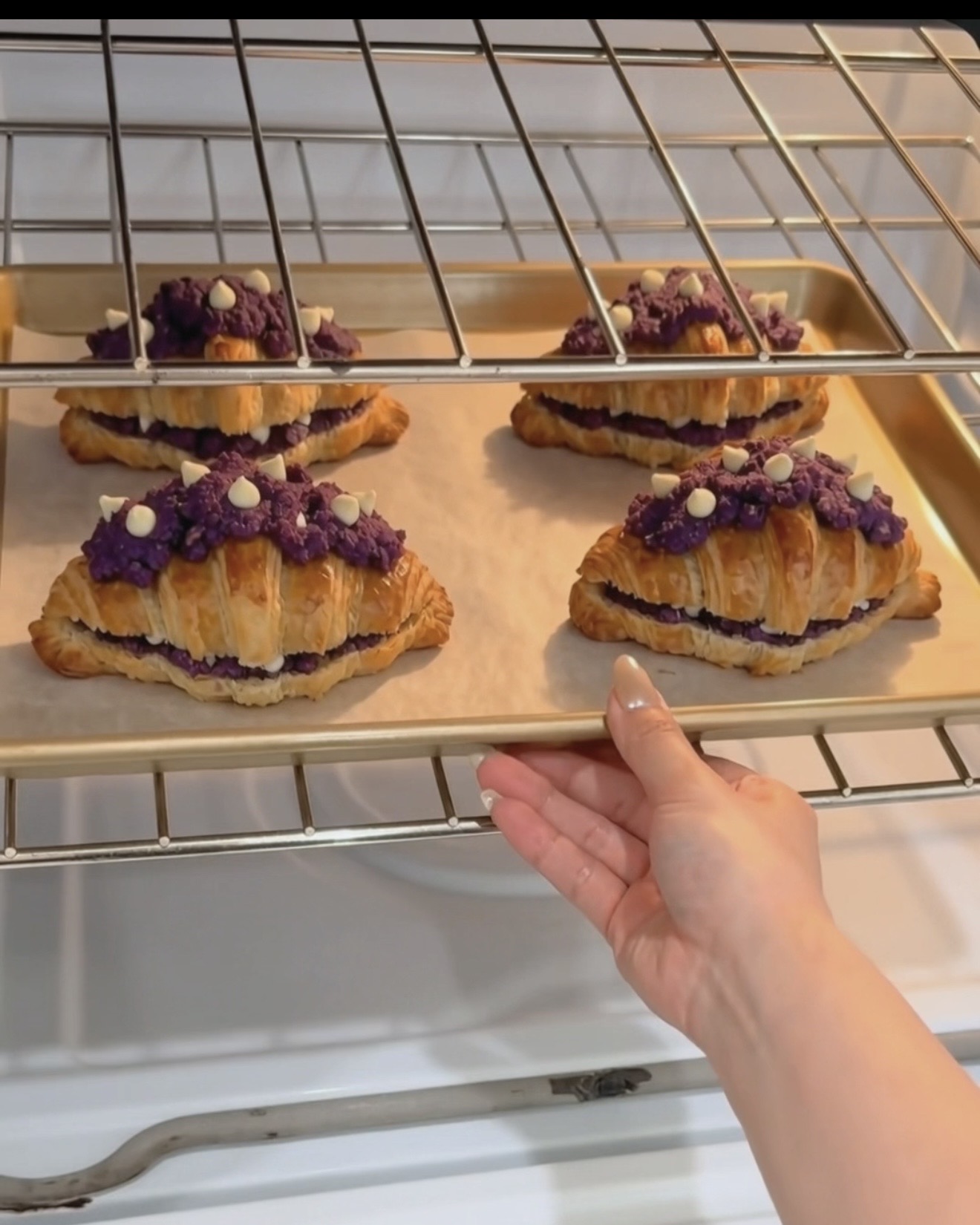 Teglia di ube crookies Ube Nolia appena sfornati con strati di croissant dorati e topping di biscotto ube (purple yam) viola con gocce di cioccolato bianco