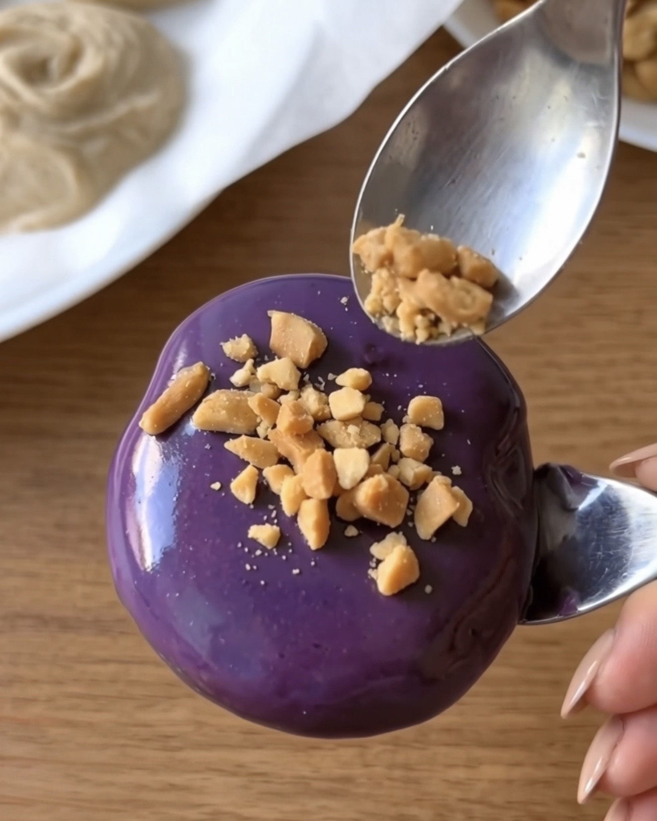 Arachidi tostate tritate sparse su un morso di frozen yogurt Ube Nolia ricoperto di cioccolato bianco viola all'ube