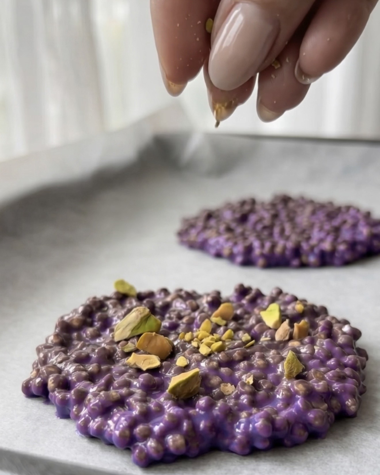 Pistacchi tritati che guarniscono bocconcini di quinoa viola all'ube di Ube Nolia