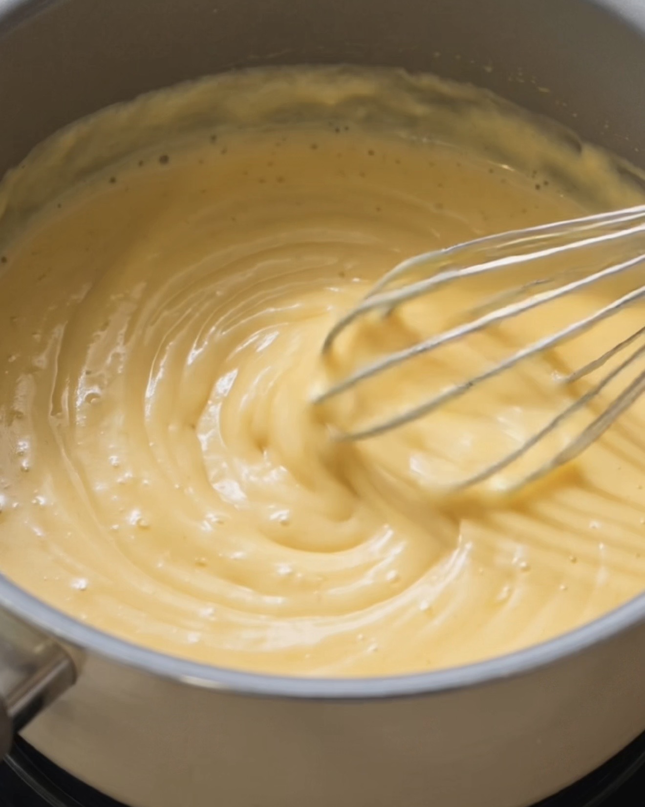Latte di cocco e latte condensato che si scaldano insieme per fare la base del ripieno di ube halaya per ube dadar gulung