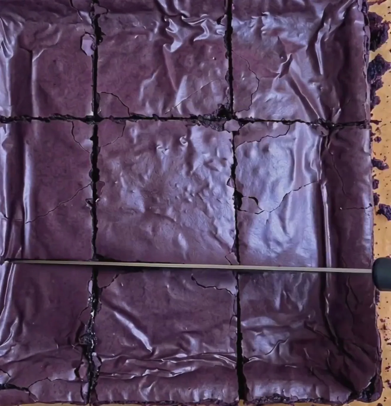 Brownies ube super fudgy cotti con una cima lucida e increspata di colore viola intenso, tagliati in 9 quadrati con Ube Nolia powder