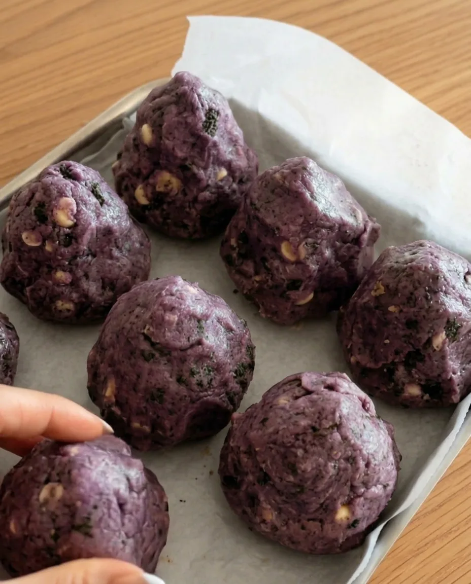 Palline di impasto ube Oreo viola su carta forno pronte per essere congelate per biscotti corposi stile New York