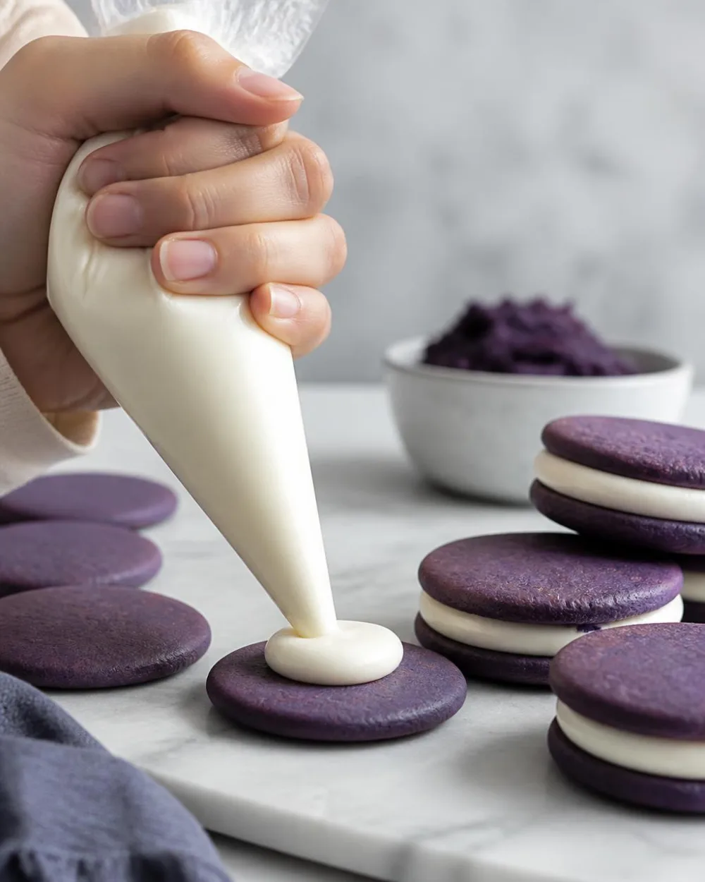 Farcire i biscotti Ube Oreo – spremere la ganache al cioccolato bianco sui wafer viola di ube | Ube Nolia