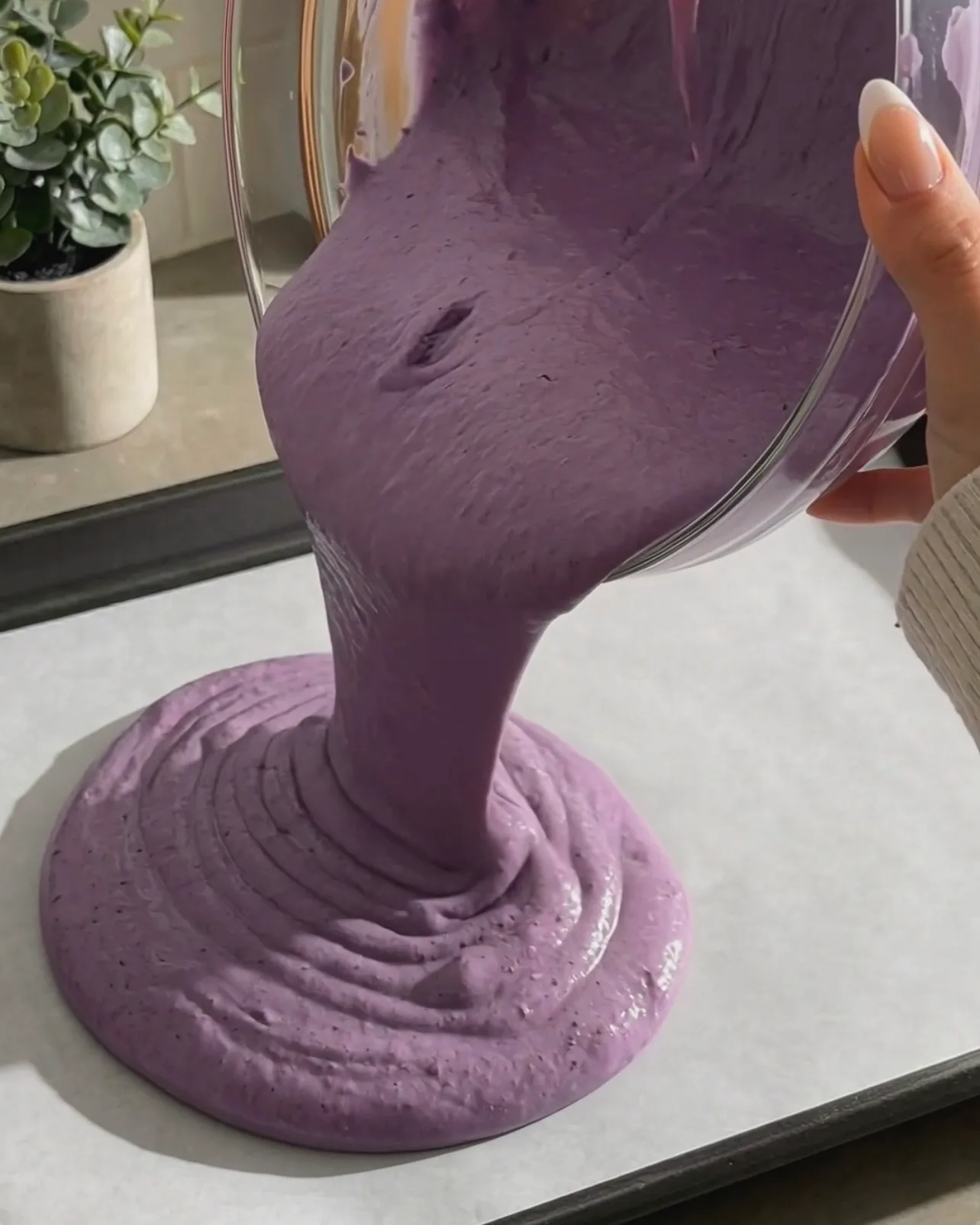 Versare l'impasto vibrante di chiffon cake viola all'ube su una teglia foderata di carta forno di Ube Nolia