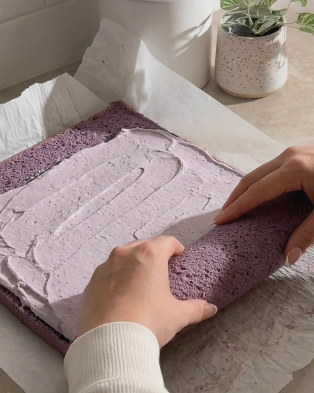 Spalmare la panna montata all'ube sulla chiffon cake viola e arrotolarla di Ube Nolia