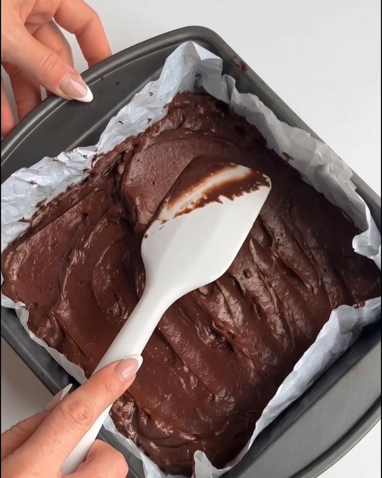 Impasto liscio per brownie al cioccolato Ube Dubai steso in una teglia quadrata rivestita di carta forno, pronto per la cottura secondo la ricetta Ube Nolia