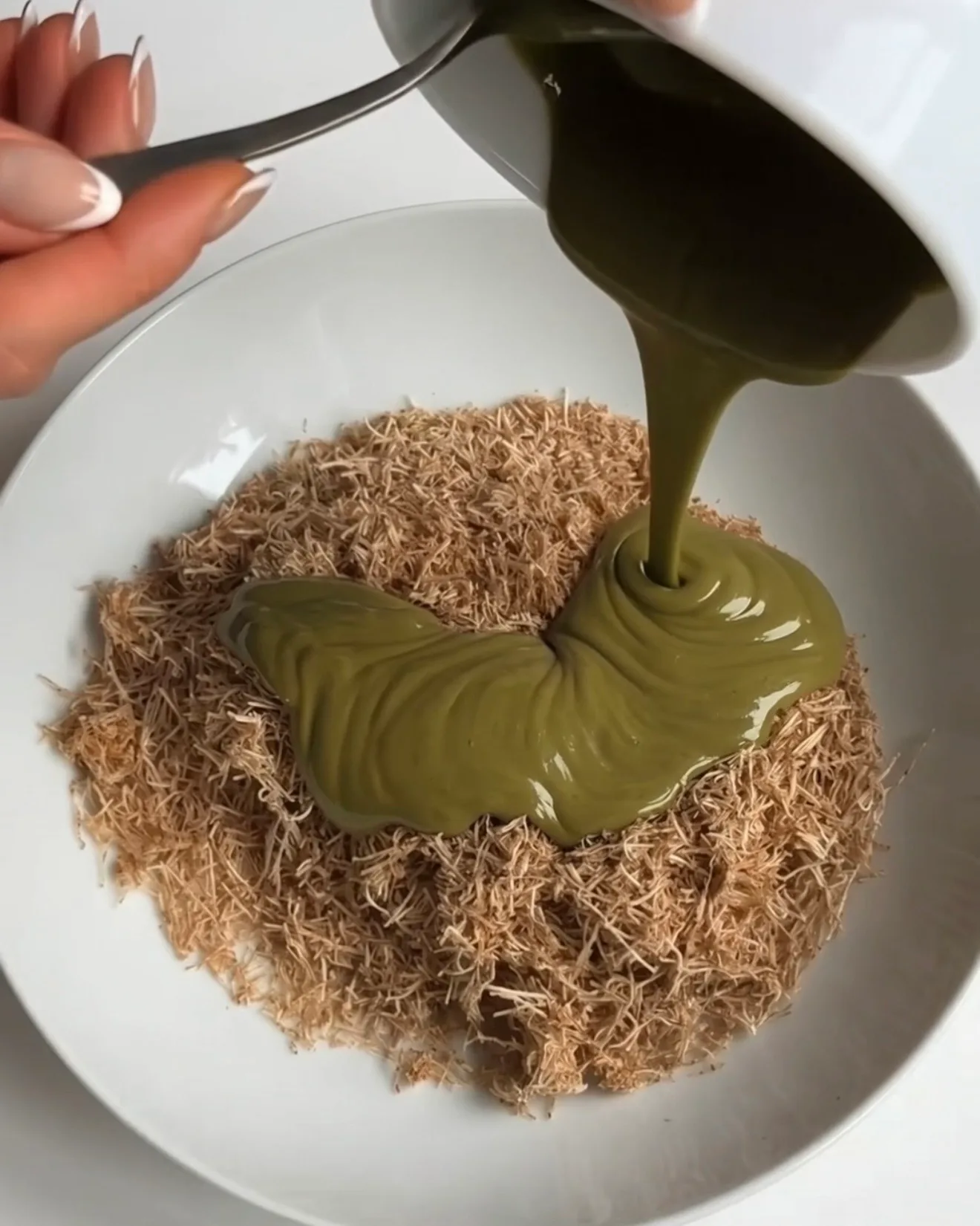 Crema di pistacchio versata su una ciotola di pasta kataifi tostata per il ripieno delle barrette brownie al cioccolato Ube Dubai di Ube Nolia