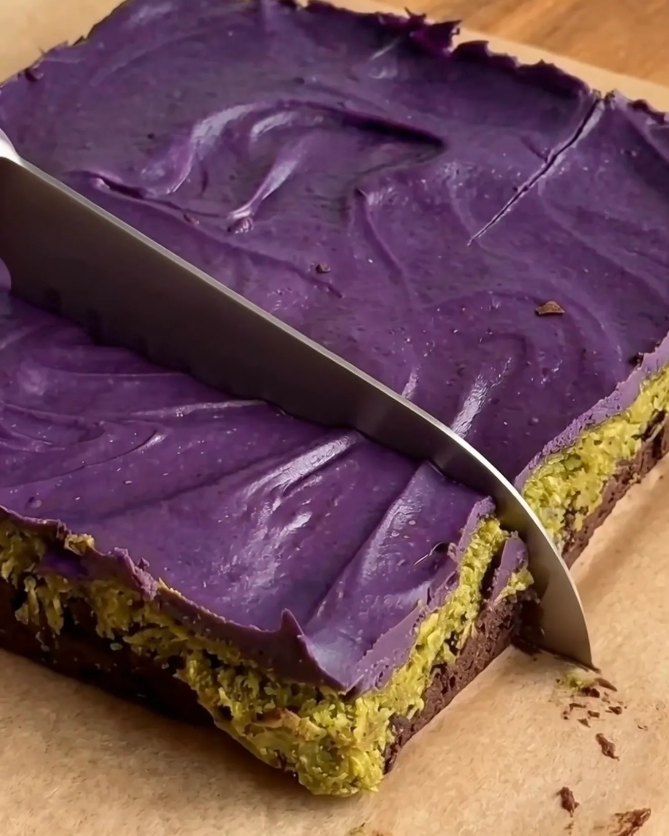 Affettare le barrette brownie al cioccolato Ube Dubai fredde mostrando gli strati di brownie, kataifi al pistacchio e cioccolato bianco ube di Ube Nolia